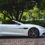 white Aston Martin convertible parked near trees